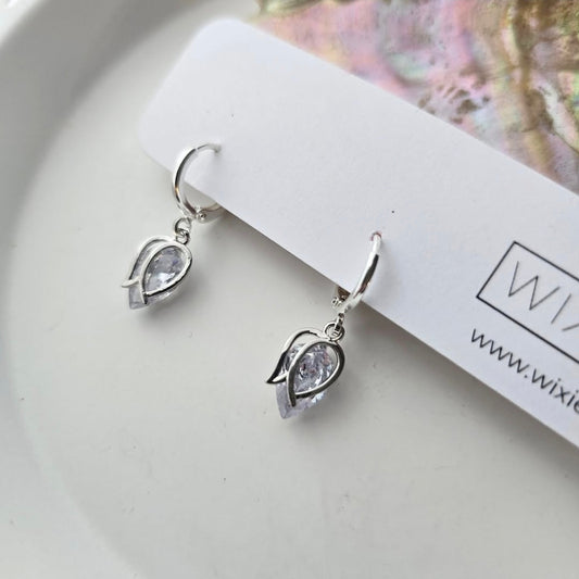 Tulip Huggie Hoops with light purple gemstones in silver plated design on white display card by My Store