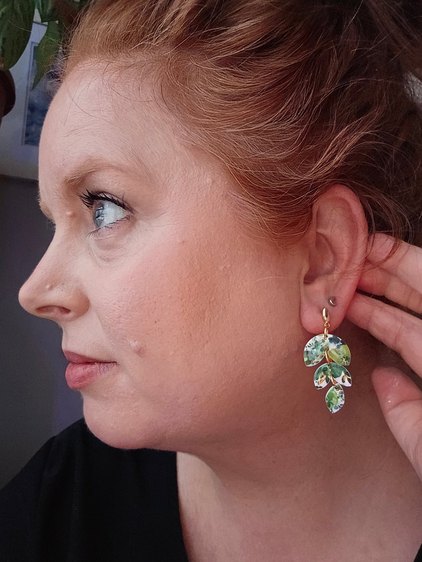 Wixies Green Floral Dangles worn by model, featuring delicate green leaf design with gold accents against dark background