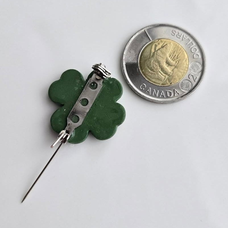 Wixies Shamrock Brooch shown from the back with pin fastener next to Canadian two dollar coin for scale