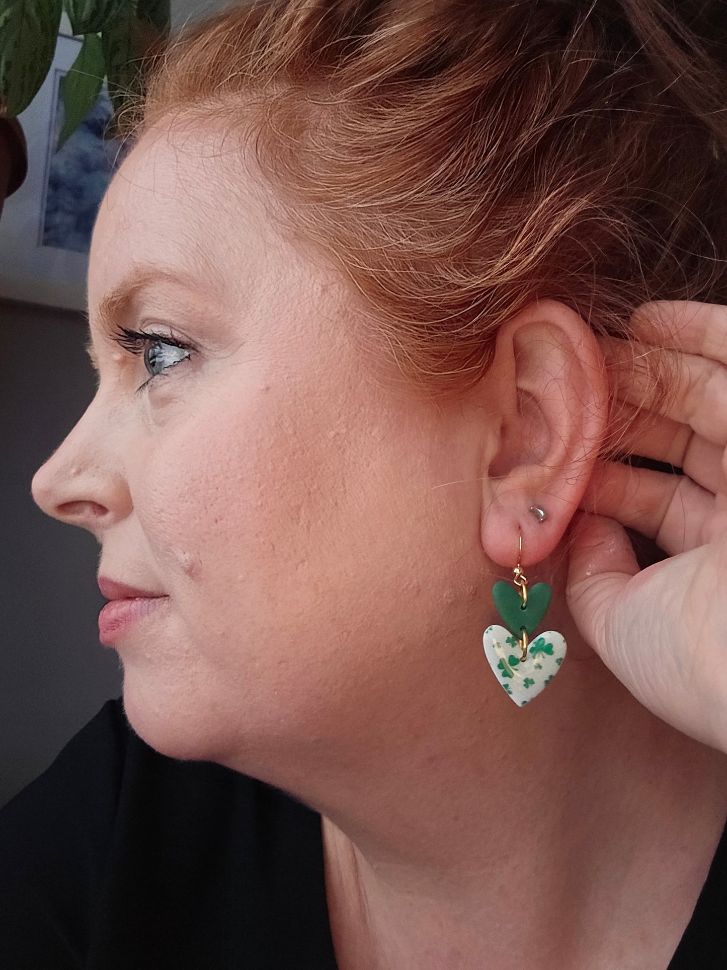 Lovely Clover Dangles by wixies worn on model featuring green and white heart shapes with clover details and gold hooks