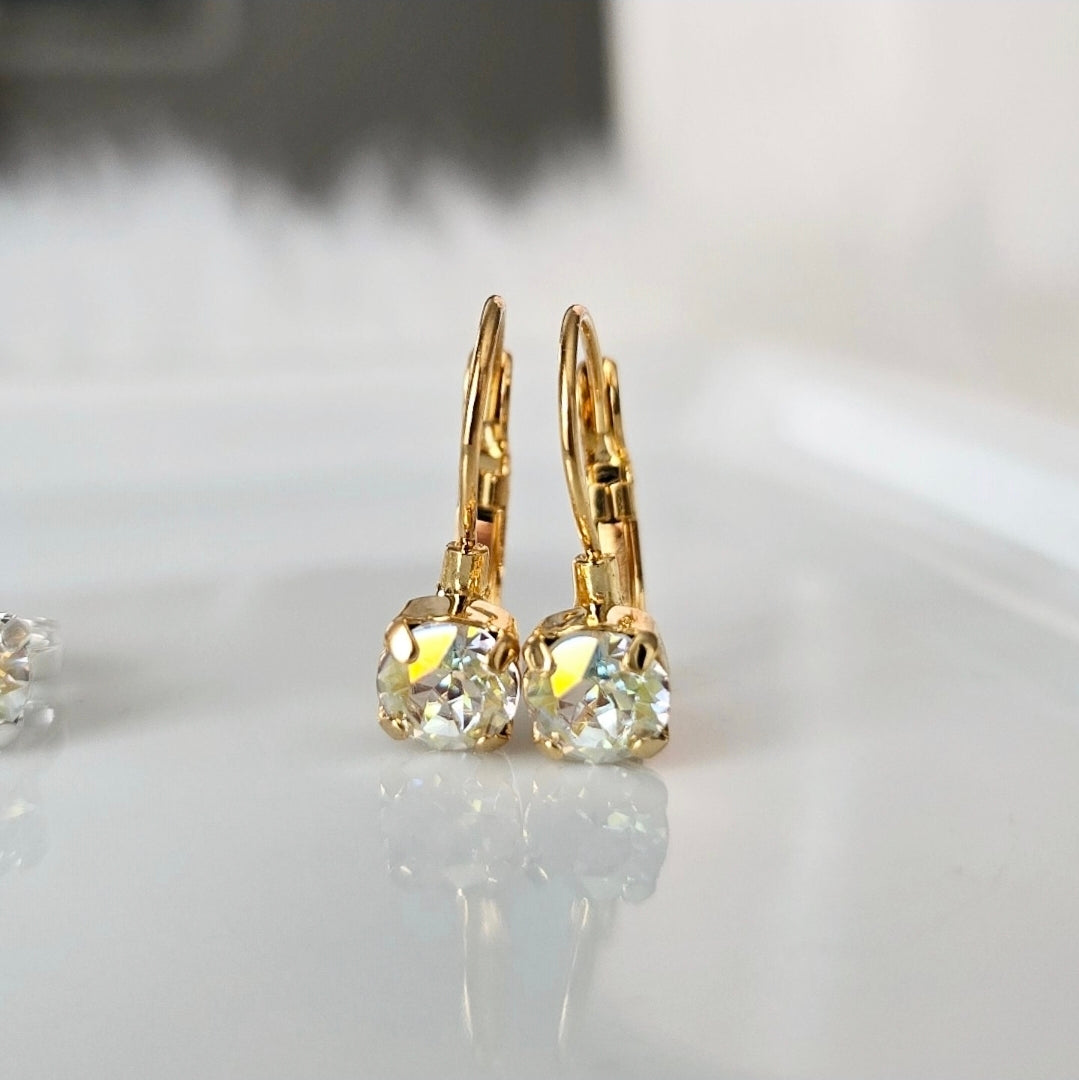 Image of a dainty pair of french lever back style earrings in a gold plated brass setting. The earrings feature one singular crystal gem that is about 6mm in diameter.